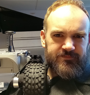 
        Dr Phil Peterson with a small robot on his shoulder
        