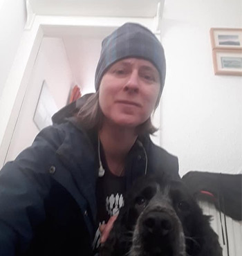 Marja, wearing a headscarf, posing with her dog